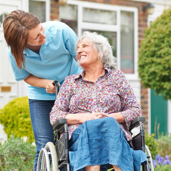 Smiling elder woman in wheelchair with female carer