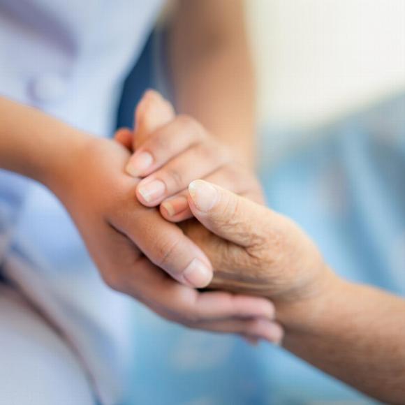 Close up of young woman's hand holding elderly person's hand