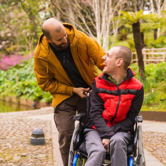 Smiling man with disability speaking with male care companion
