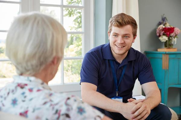 Smiling male carer speaking with senior woman