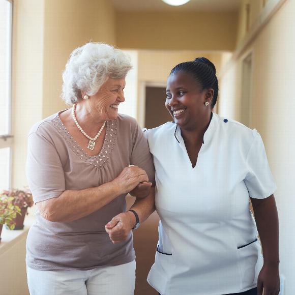 Smiling elderly woman and care worker walking together down hallway